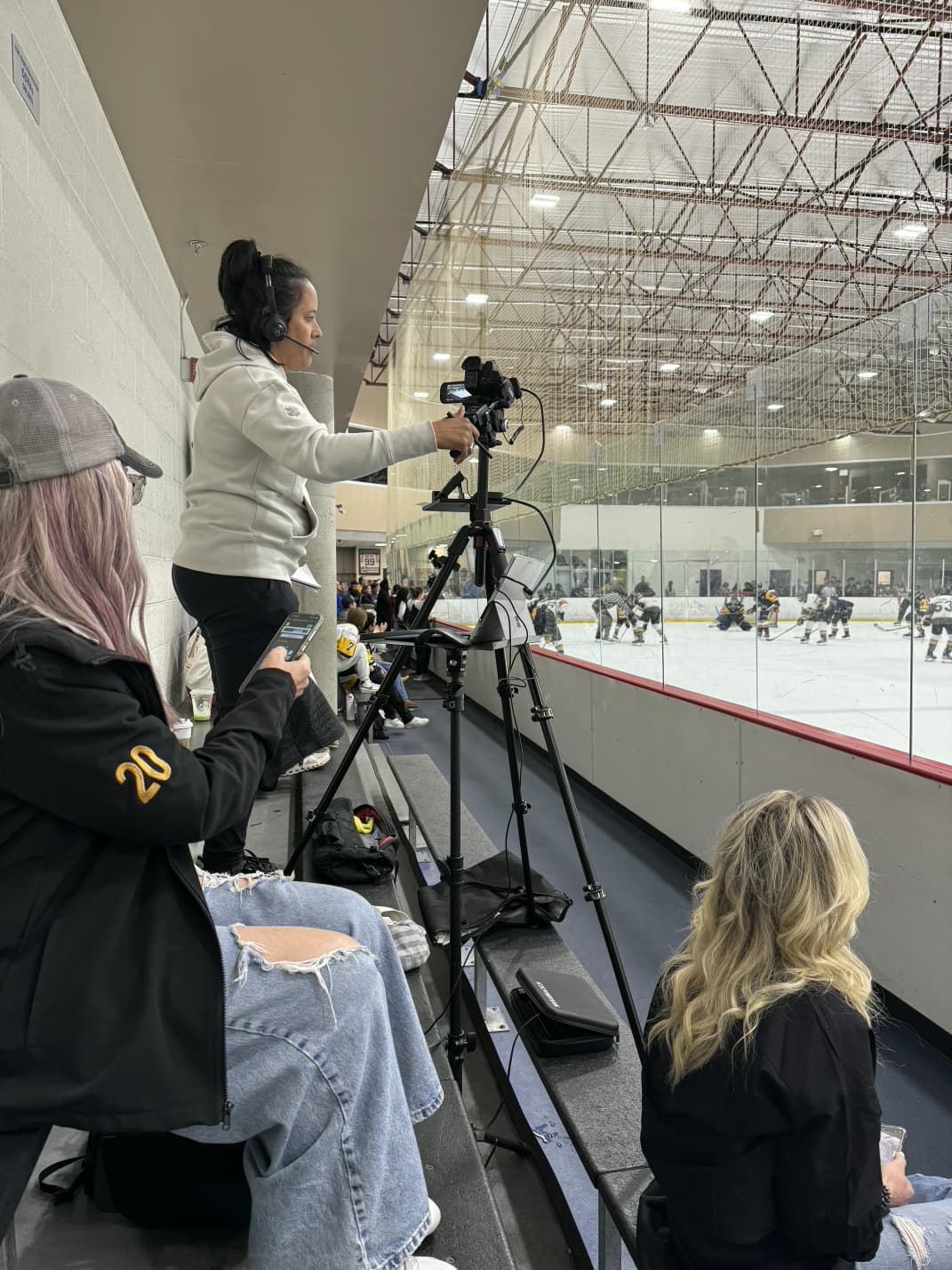 Summer manages her streaming setup during a hockey game, focused intently on delivering professional play-by-play commentary while tracking the action