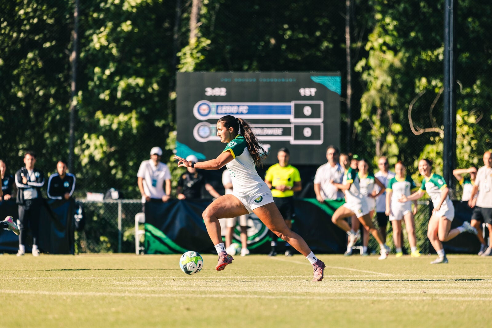 A player breaks forward at The Soccer Tournament, with the pitch-side LED scoreboard showing 3:02 in the first half