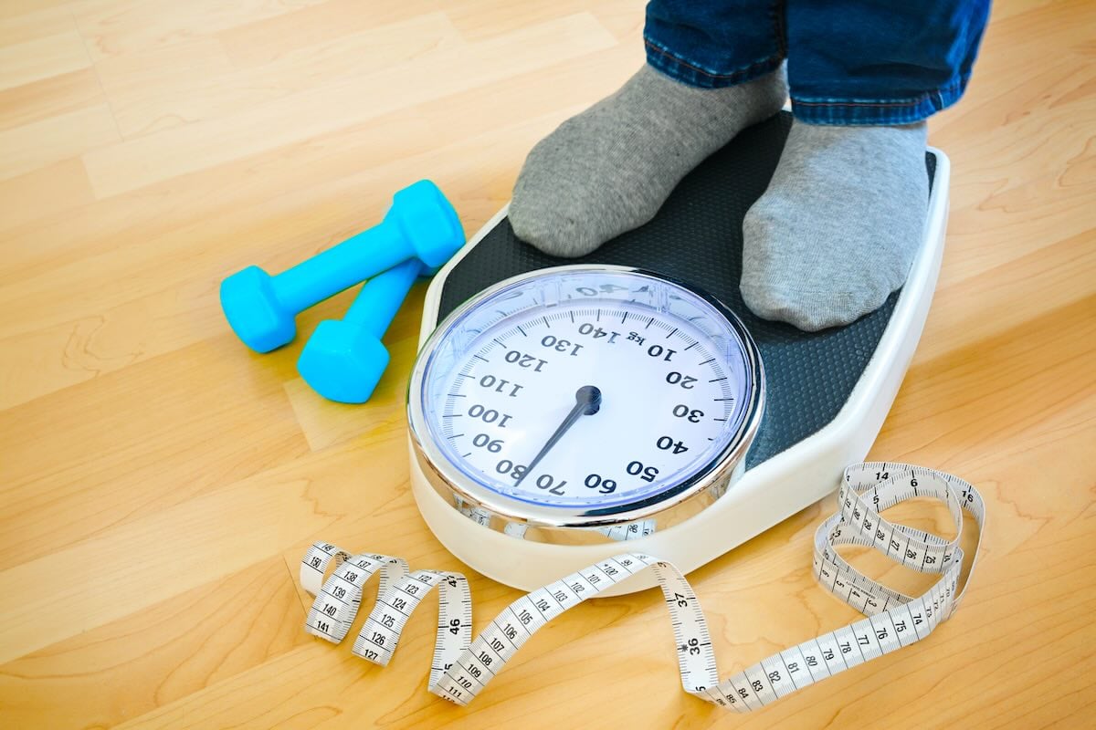 A man standing on scales to monitor weight loss